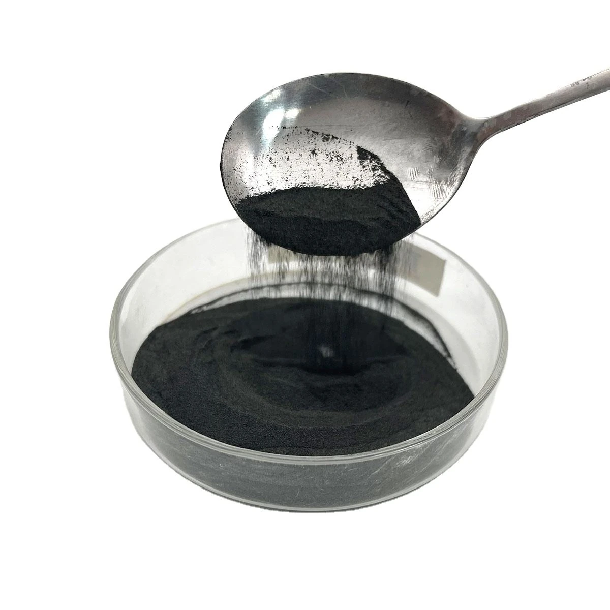 Alpha silicon carbide powder flowing from a spoon into a glass dish